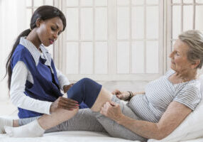 Physiotherapy - therapist doing leg stretching exercises with senior  patient
