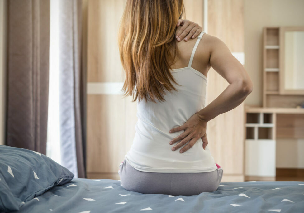 Woman suffering from back ache on the bed, healthcare and problem concept